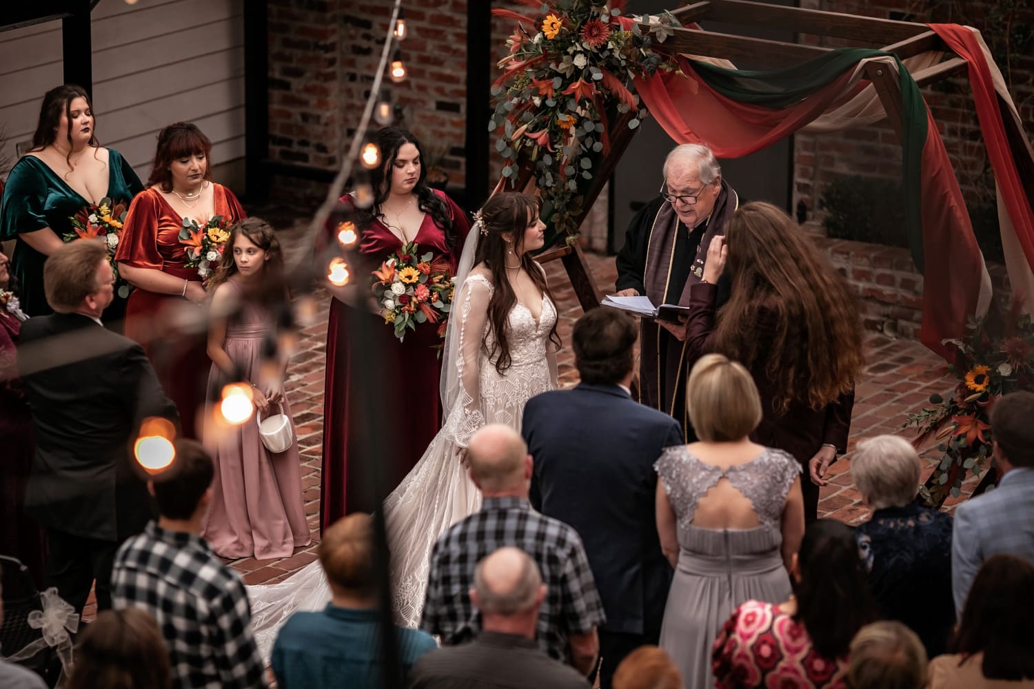 ahnvee photography wedding ceremony wedding guests stand around bride and groom during vows in a brick outdoor courtyard