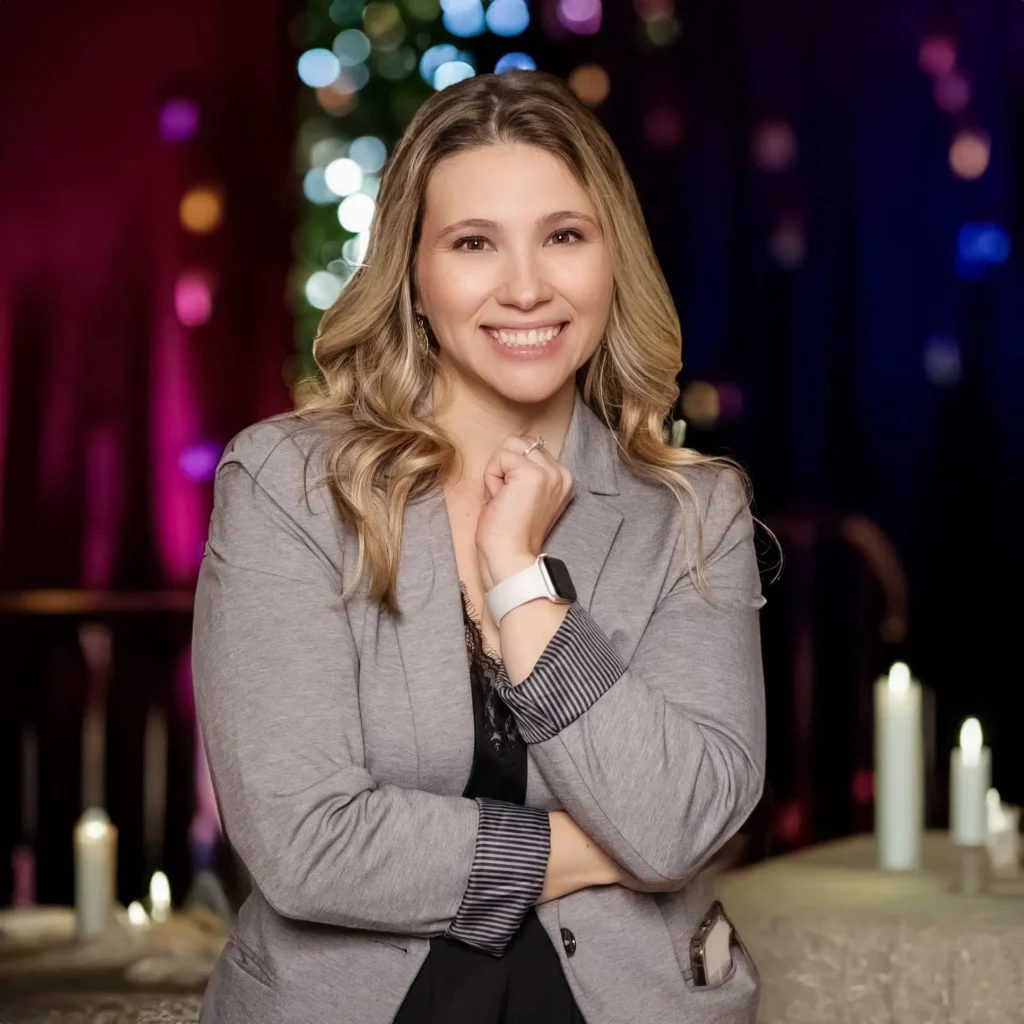 Ashley Lerma, second photographer for Ahnvee Photography, a creative Louisiana photographer, smiling in a professional headshot with soft, colorful background lighting